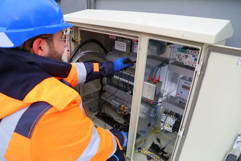 An electrician working at an outdoor electrical cabinet